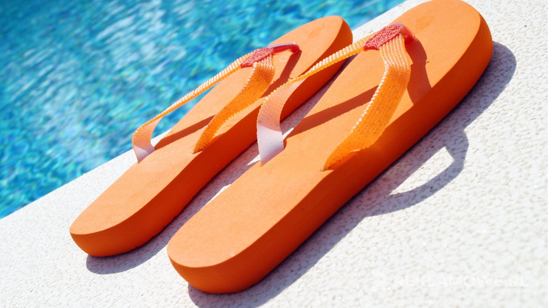 Jak klapki reklamowe mogą zwiększyć rozpoznawalność marki? Klapki reklamowe leżące na plaży jako narzędzie marketingowe